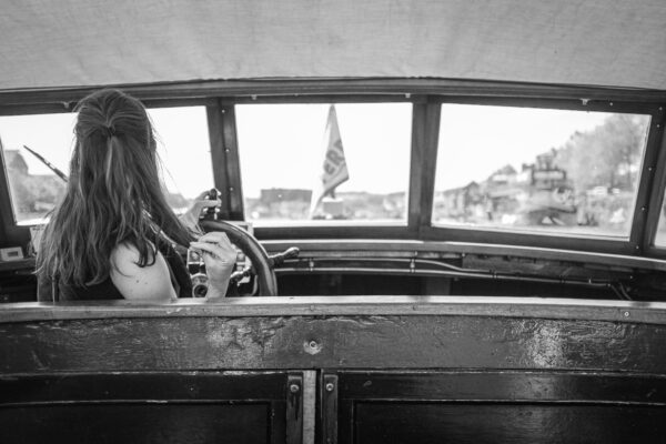 A driver at the helm of  the Bristol Ferryboat Company's boat Emily idly plays with her hair while at the helm